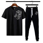 Black t-shirt and pants set with lion design on hangers against a white background